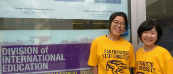 Two female international students standing in front of DoIE entrance.