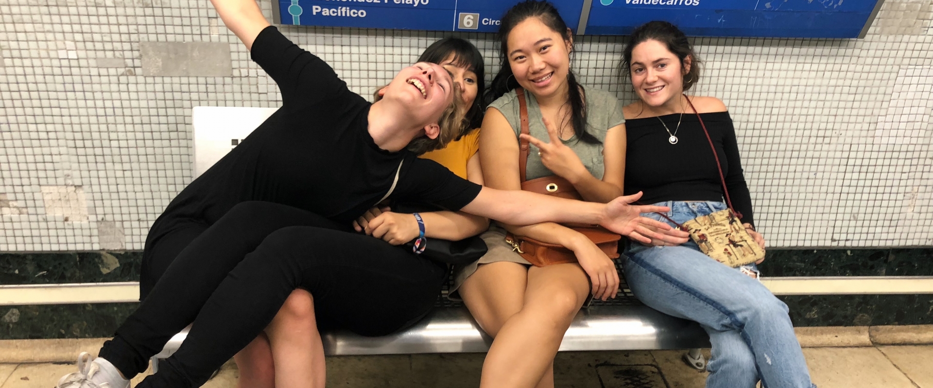 Four girls on a bench at a train station 